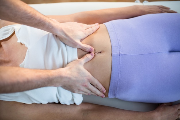 Male physiotherapist giving stomach massage to female patient Premium Photo
