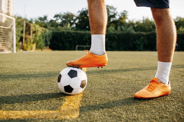 フィールドのライン上にボール立って男性のサッカー選手の足 屋外スタジアムでのサッカー選手 サッカーの試合前のトレーニング プレミアム写真
