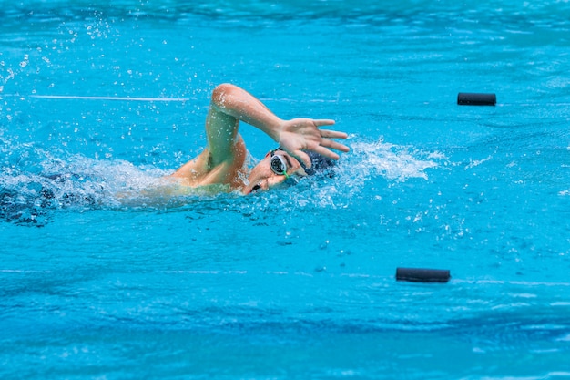地元のプールでフリースタイルのスイミングストロークをやっている男性の水泳選手 プレミアム写真