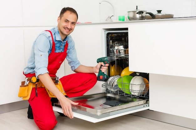 Premium Photo | Male technician sitting near dishwasher in kitchen