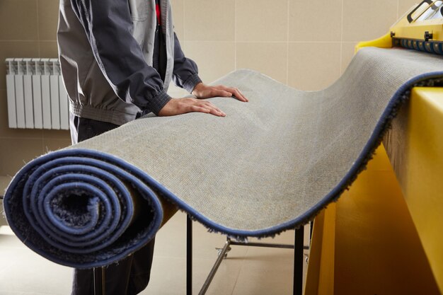 Male worker cleaning carpet on automatic washing machine equipment and dryer in the laundry room Premium Photo