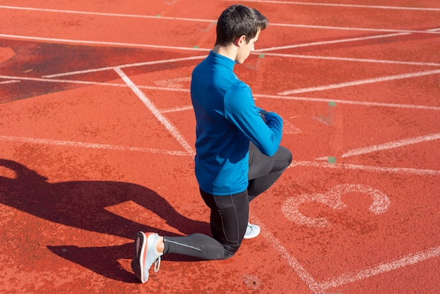 Premium Photo Man Athlete On The Starting Line Of A Running Track At The Stadium Resting On