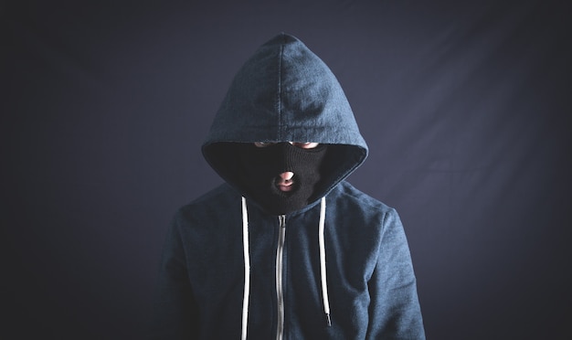 Premium Photo | Man black hoodie with ski mask standing on a dark ...