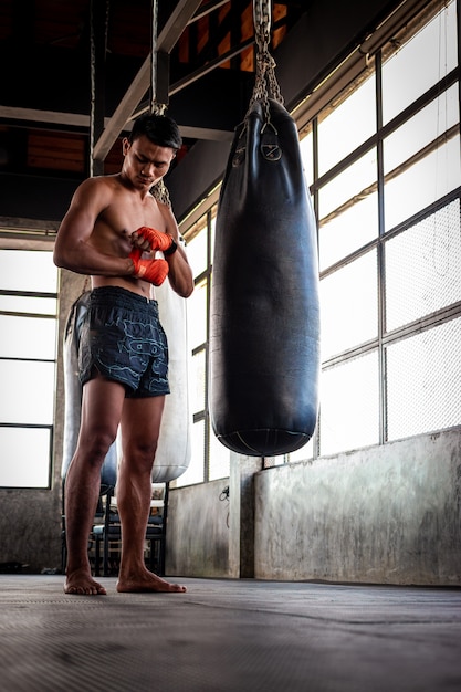 Premium Photo | Man boxer wrapping his hand in boxing arena sport.