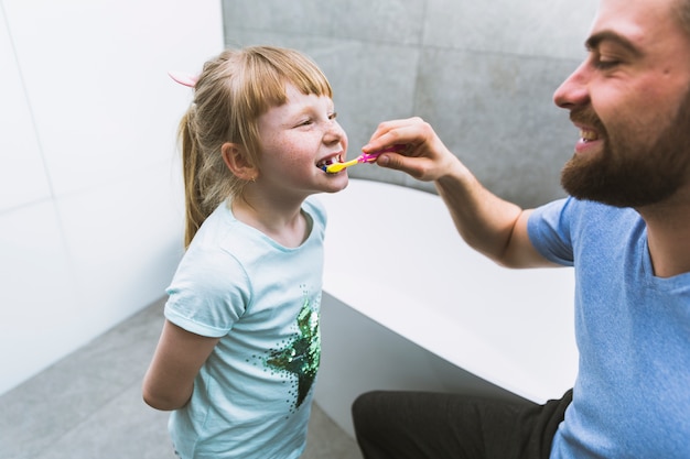 Man Brushing Teeth Of Daughter Free Photo
