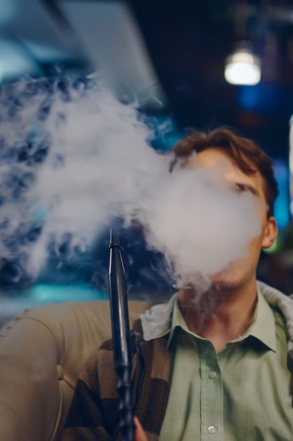 Premium Photo | Man in cafe smoking hookah thick smoke from shisha ...