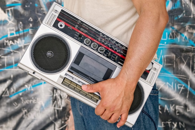 Premium Photo Man Carries A Vintage Boombox Next To A Wall With Graffiti