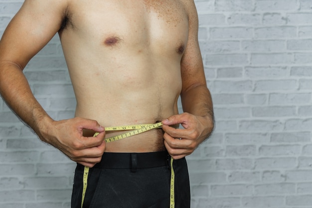 Man check out his body fat with measuring tape Premium Photo