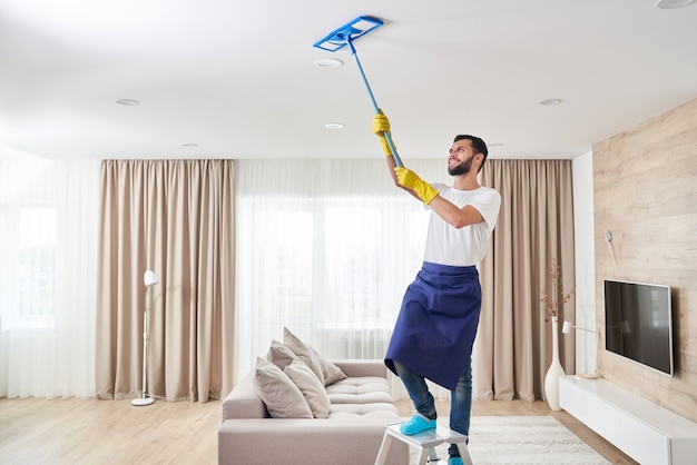 Premium Photo | Man cleaning ceiling and lamps in living room. house ...