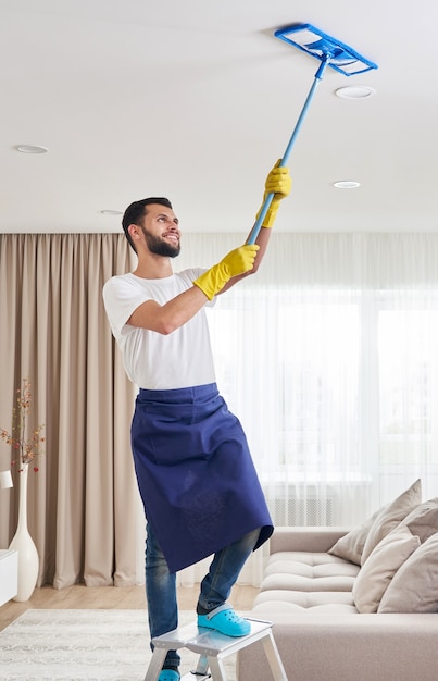 Premium Photo | Man cleaning ceiling and lamps in living room. house ...