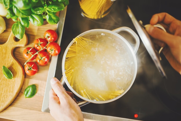 Man cooking pasta in boiling water Free Photo