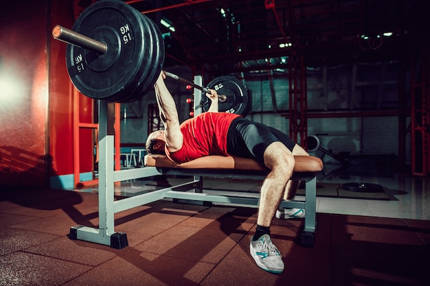 Premium Photo | Man doing bench press workout in gym