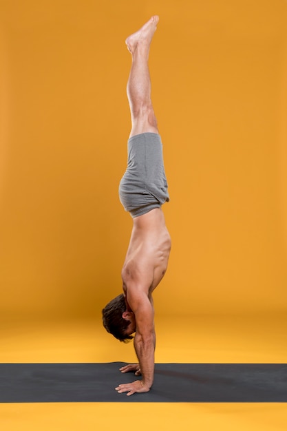 Free Photo Man Doing Handstand Pose On Yoga Mat