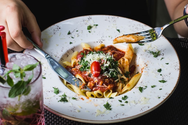 Free Photo | Man eating bolognese penne pasta garnished with herbs