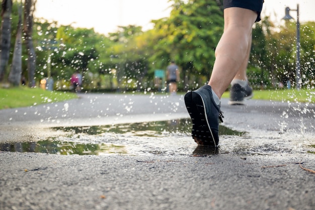 Man exercise running through puddle splashing his shoes. Premium Photo