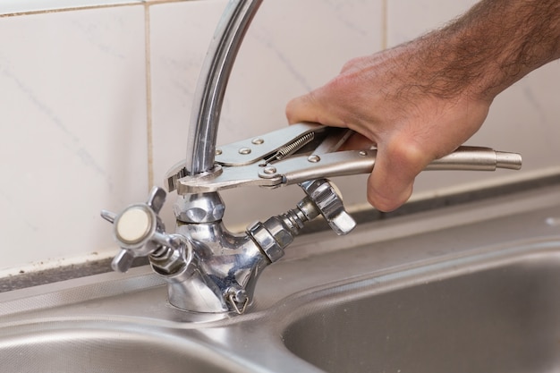 Premium Photo | Man fixing tap with pliers