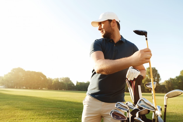 Man golfer taking out the golf club from a bag | Free Photo