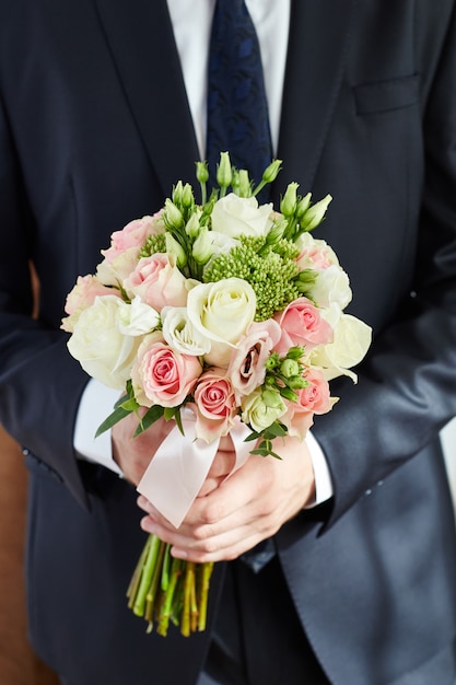 Man groom holds the bridal bouquet. guy in jacket Premium Photo