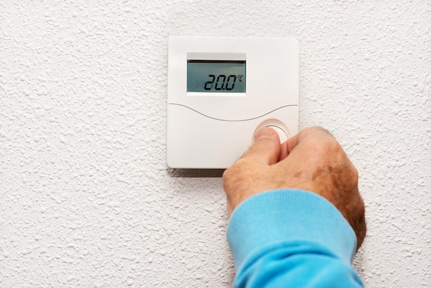 Premium Photo | Man hand adjusting thermostat at home. celsius ...