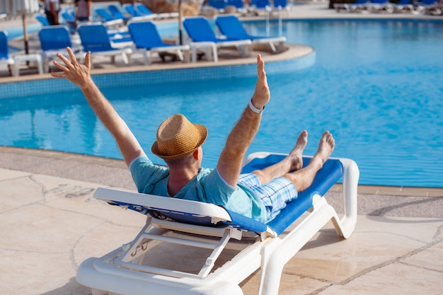 Premium Photo | Man in hat sunbathing on a sun lounger by the pool