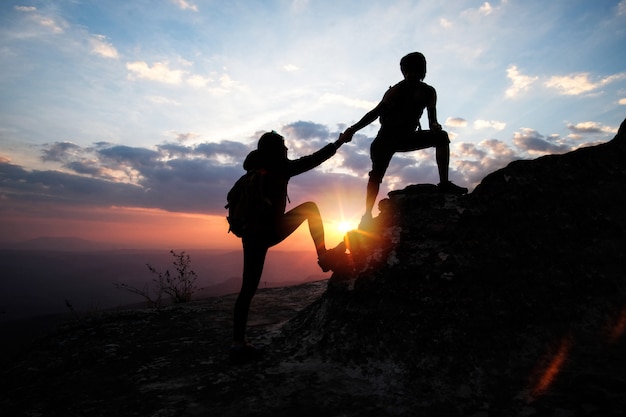 Man helping a woman to up on the mountain in hiking activity ...
