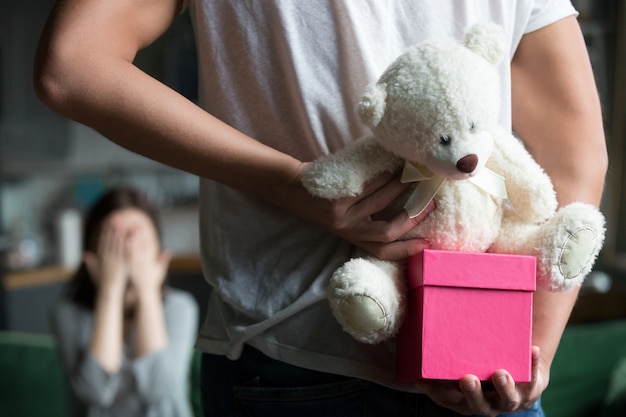 Man hiding gift making romantic surprise for wife, rear closeup Free Photo