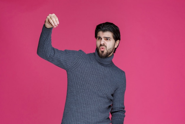 Man holding something in the hand and looking to it. Free Photo