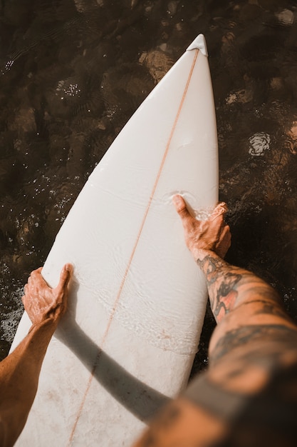 Free Photo | Man holding surf board on water near coast