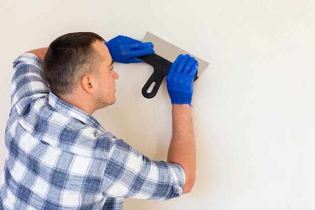 Free Photo | Man holding a trowel while working on wall