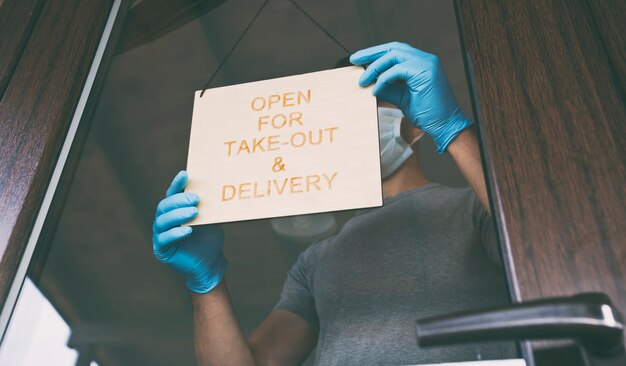 Premium Photo Man Holds The Wooden Sign With Text Open For Take Out And Delivery