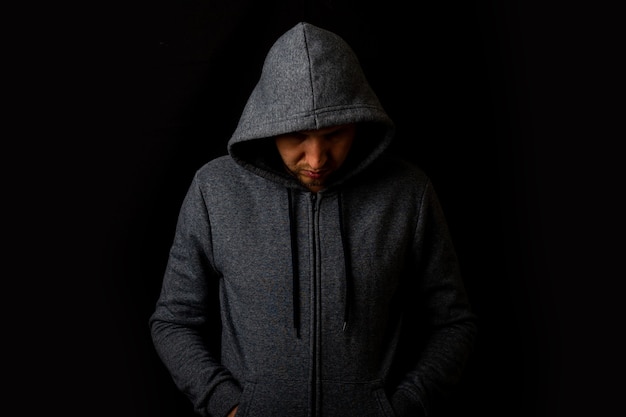 Premium Photo | Man in a hood and a hoodie on a dark background.