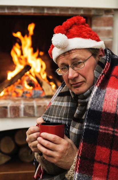 火の背景に温かい飲み物のカップと暖かい服を着た男 プレミアム写真