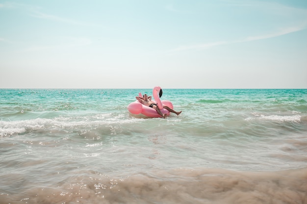Man is having fun on pink flamingo inflatable pool float Premium Photo