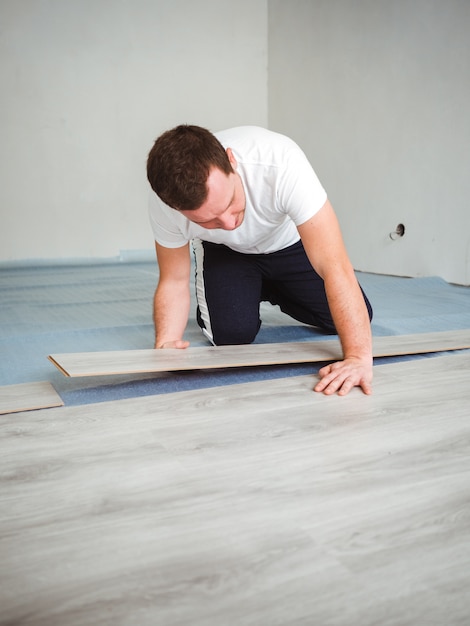 A Man Is Laying Laminate Flooring The Repair Process In The Room