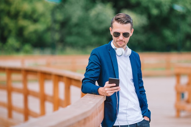 Man is reading text message on mobile phone while walking in the park Premium Photo