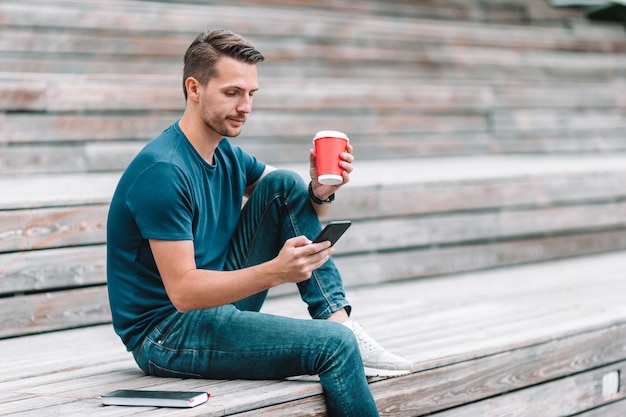 Man is reading text message on mobile phone while walking in the park Premium Photo
