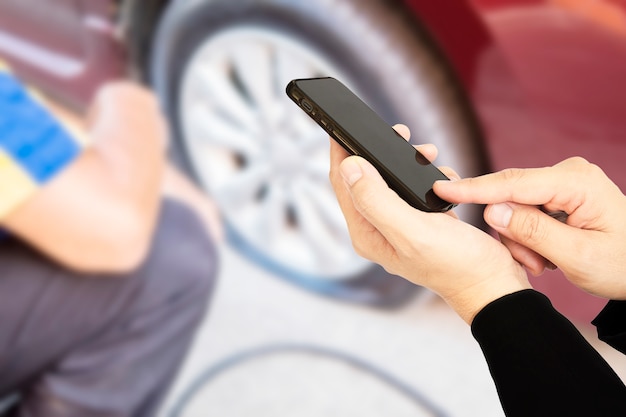 Man is using mobile phone calling somebody over car flat tire background Free Photo