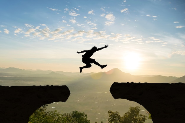 Premium Photo | Man jump mountain cliff sun light over silhouette