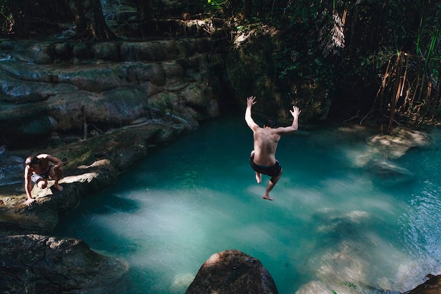 Man jumping into a natural pond Free Photo