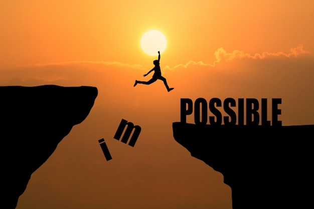 Man jumping over impossible or possible over cliff on sunset background,Business concept idea Free Photo