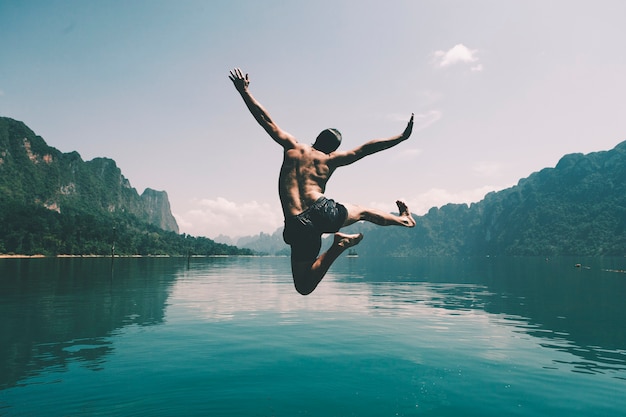 Man jumping with joy by a lake Free Photo