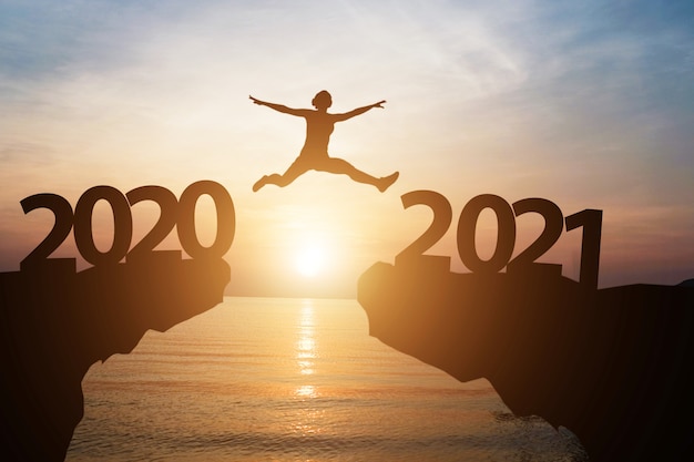 Man jumps from year 2020 to 2021 with sunlight and sea as ...