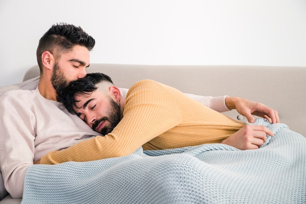 Premium Photo Man Laying On His Boyfriend S Chest Over The Sofa Against The White Wall