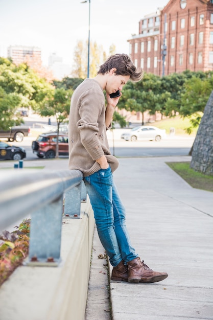 Free Photo | Man leaning on railing while talking on mobile phone