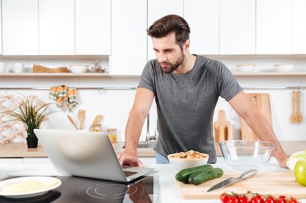 Free Photo | Man looking recipe on laptop in kitchen at home