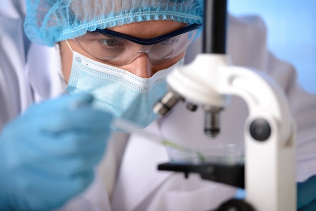 Premium Photo | A man in mask and glasses is experimenting with microscope.