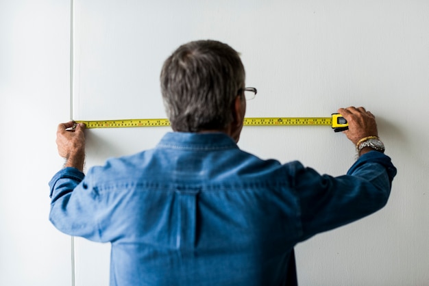 Man measuring the wall with a measuring tape Free Photo