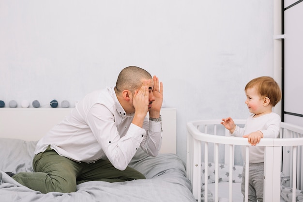 Man Playing With Smiling Little Baby In Crib In Bedroom Free Photo