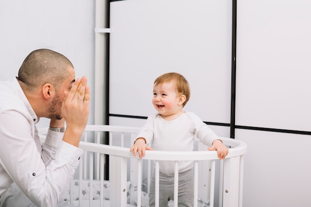 Man Playing With Smiling Little Baby In Crib Free Photo