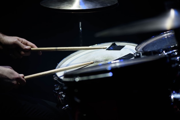Man plays musical percussion instrument with sticks closeup, a musical concept with the working drum, beautiful lighting on the stage Premium Photo